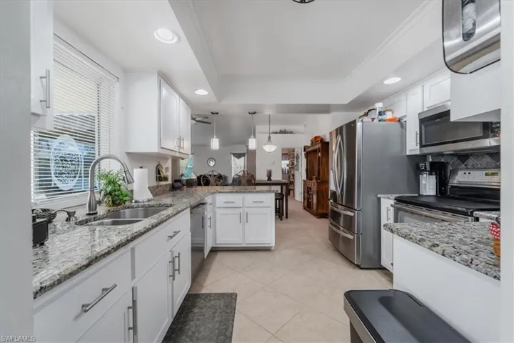 Kitchen featuring appliances with stainless steel finishes, a peninsula, white cabinets, crown molding, and recessed lighting