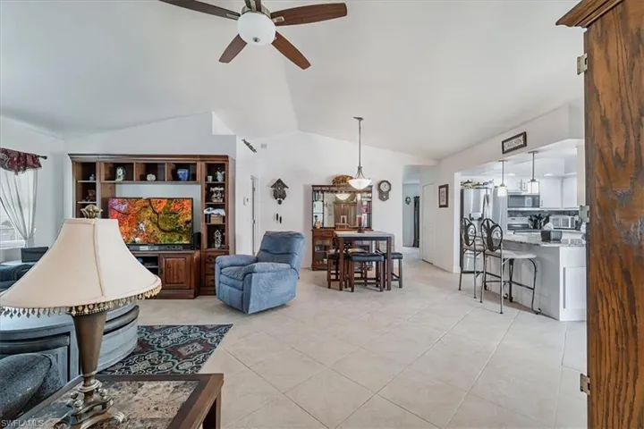 Living room with vaulted ceiling, a ceiling fan, and light tile patterned floors