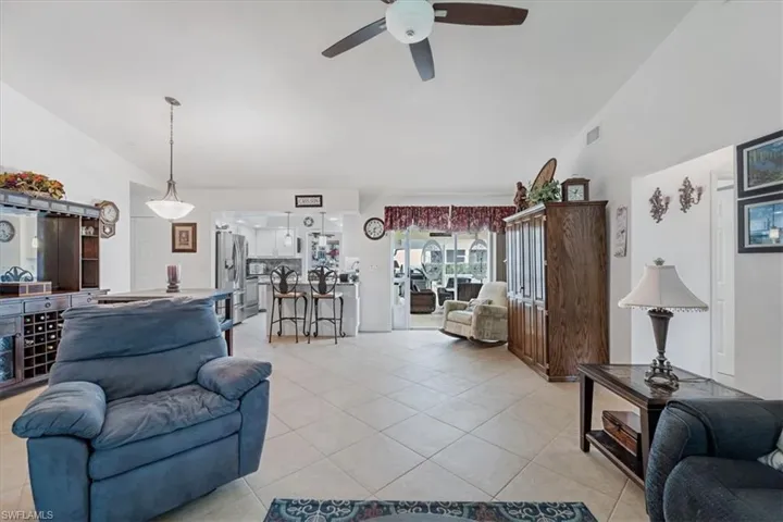 Living area with ceiling fan, light tile patterned floors, and vaulted ceiling