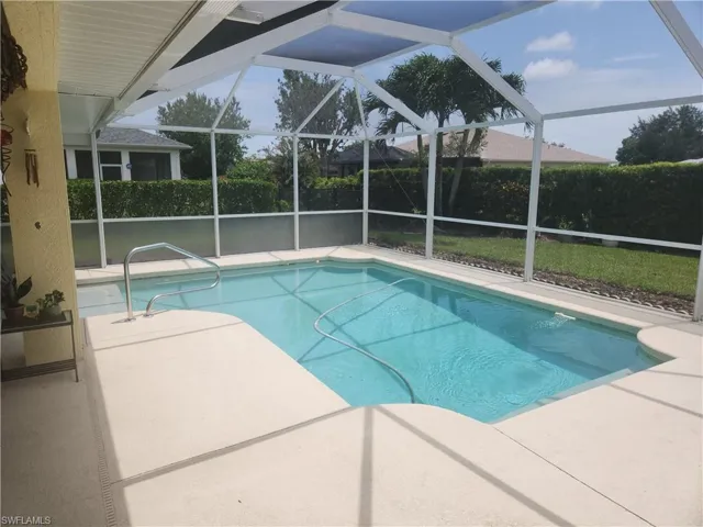 View of pool featuring a patio area and glass enclosure
