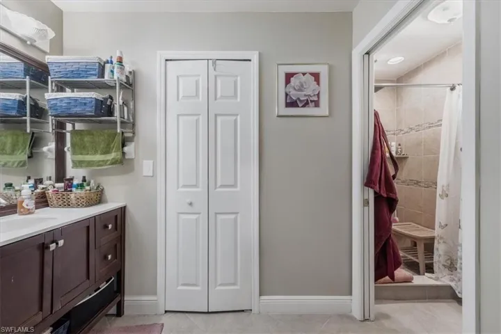 Bathroom featuring a closet, vanity, a tile shower, and tile patterned flooring