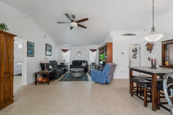 Living room with ceiling fan, light tile patterned flooring, and high vaulted ceiling