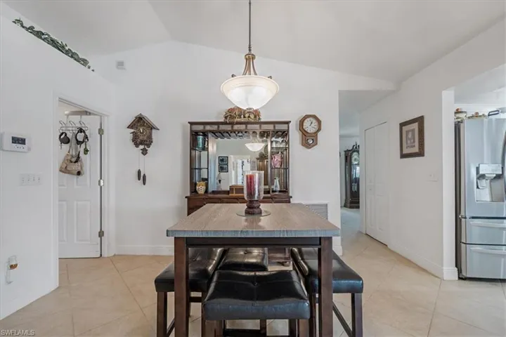 Dining room with light tile patterned floors and lofted ceiling