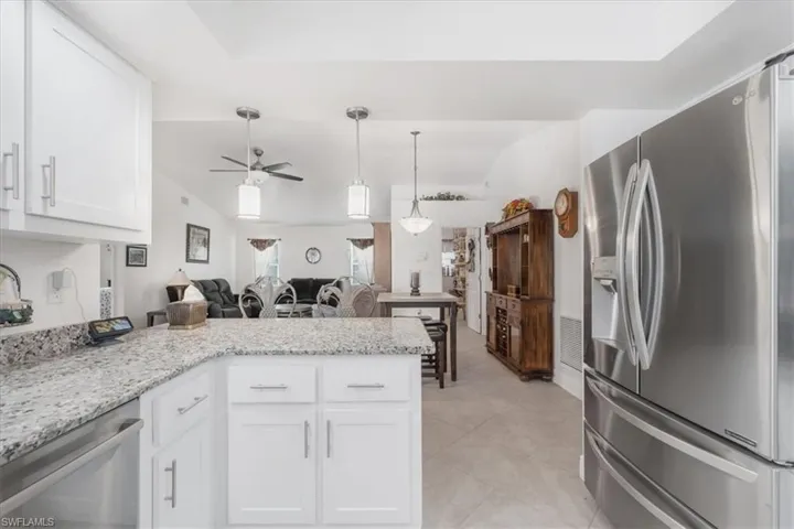 Kitchen featuring appliances with stainless steel finishes, a peninsula, white cabinetry, ceiling fan, and open floor plan