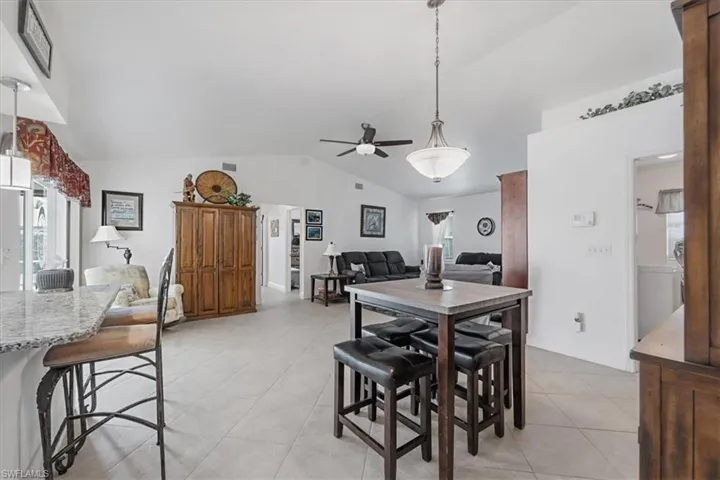 Dining area featuring light tile patterned floors, vaulted ceiling, and ceiling fan