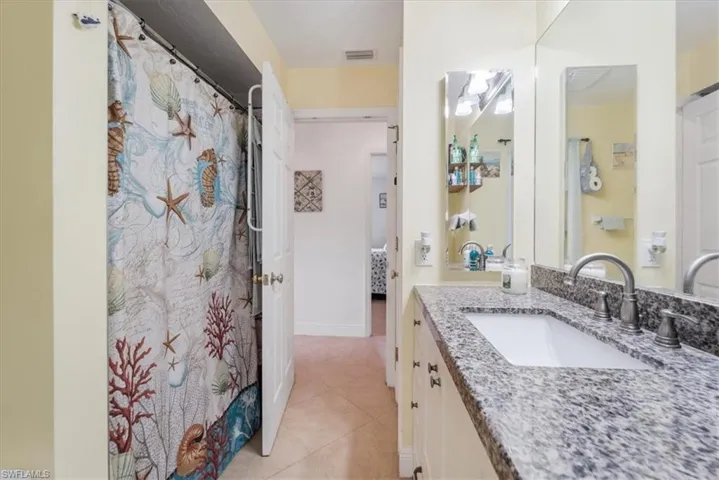 Ensuite bathroom featuring vanity, tile patterned floors, and curtained shower