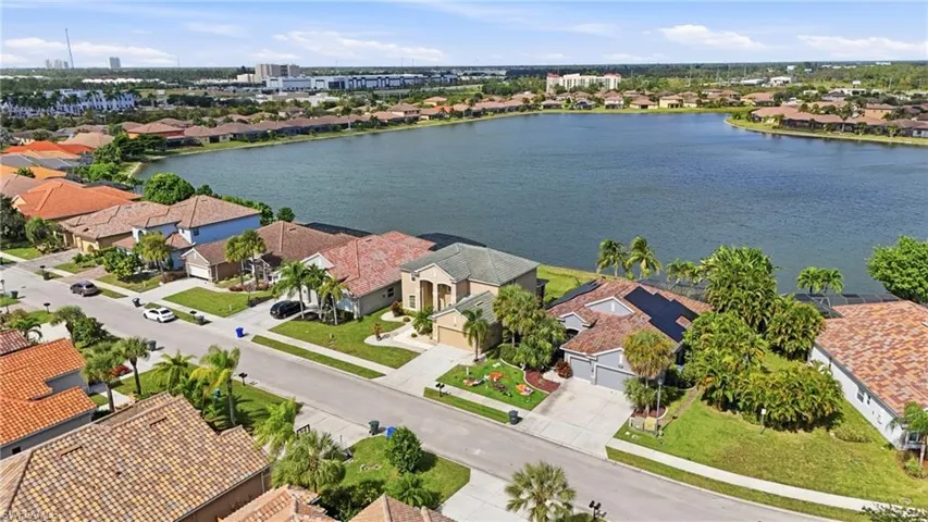 Aerial perspective of a lakefront residential community featuring tile roofing and established tropical landscaping