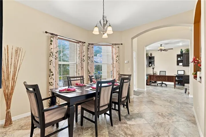 Dining area featuring multi-pane bay windows, tile flooring, an arched entryway, and a hanging metal light fixture