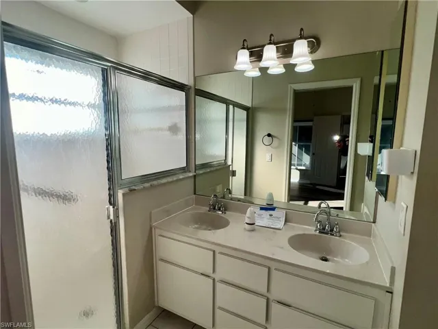 Full bathroom featuring double vanity and a stall shower