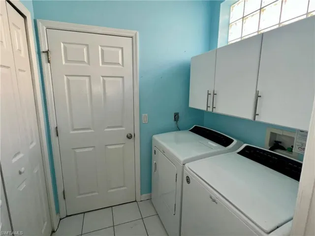 Laundry area with washer and dryer, cabinet space, and light tile patterned floors