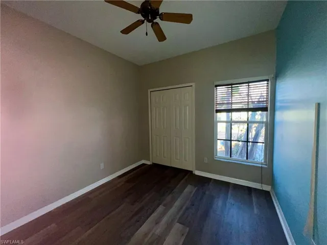 Unfurnished bedroom with dark wood-type flooring, ceiling fan, and a closet