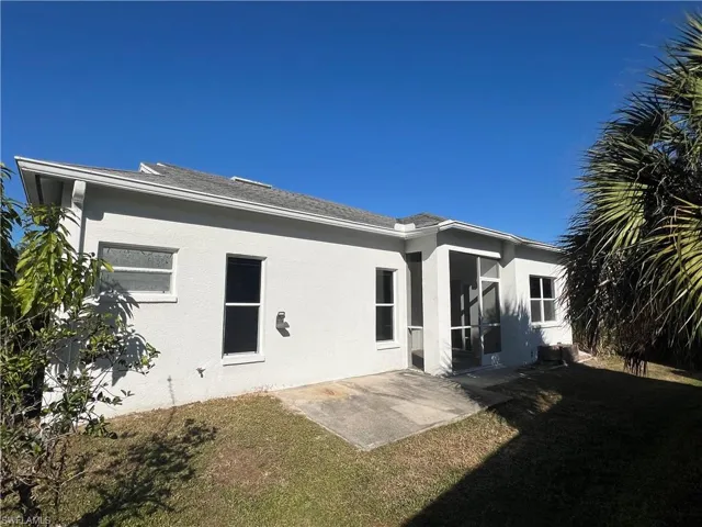 Rear view of house with a patio area, stucco siding, and a lawn