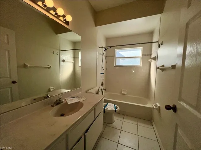 Bathroom with vanity, shower / bathtub combination, and light tile patterned floors
