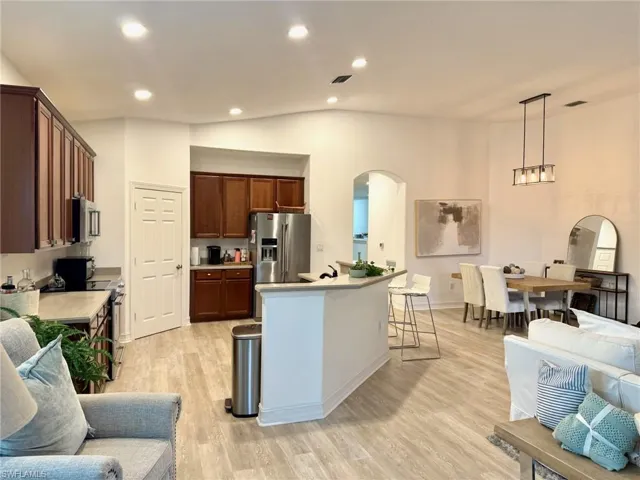 Kitchen featuring vaulted ceiling, light wood-type flooring, open floor plan, light countertops, and recessed lighting