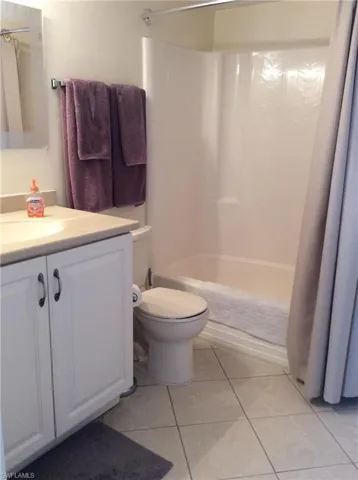 Full bathroom featuring vanity, toilet, shower / tub combo with curtain, and tile patterned flooring