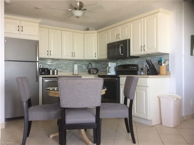Kitchen featuring stainless steel appliances, ceiling fan, light tile patterned floors, and backsplash