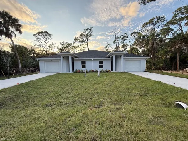 Ranch-style home with a garage, a front yard, driveway, and stucco siding