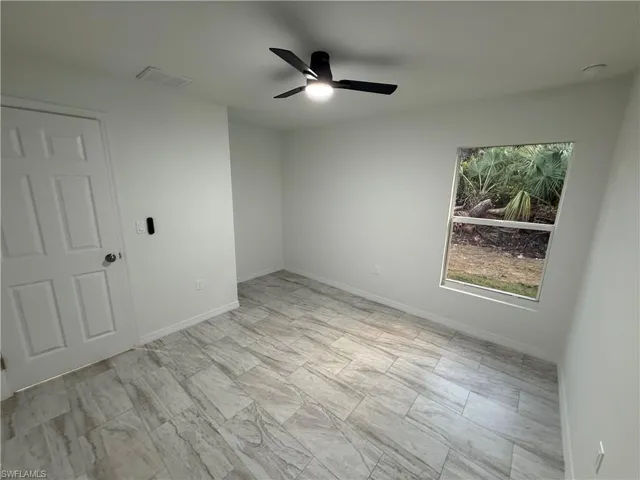 Unfurnished room with a ceiling fan and baseboards