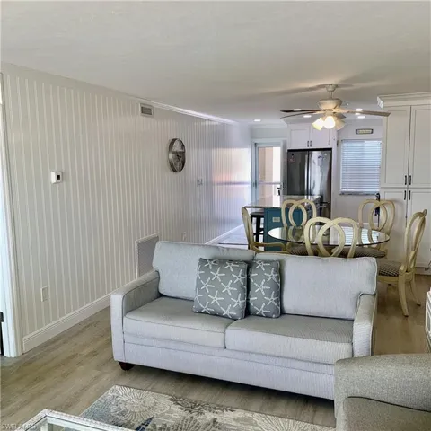 Living area with a ceiling fan, crown molding, and light wood-style floors