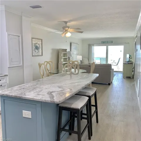 Kitchen featuring a kitchen breakfast bar, light stone counters, ceiling fan, a center island, and open floor plan
