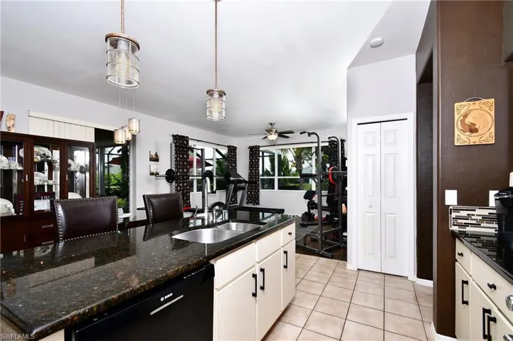 Kitchen featuring ceiling fan, black dishwasher, white cabinetry, light tile floors, and pendant lighting