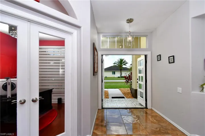 Foyer entrance with  tile flooring, a chandelier, and french doors to the den
