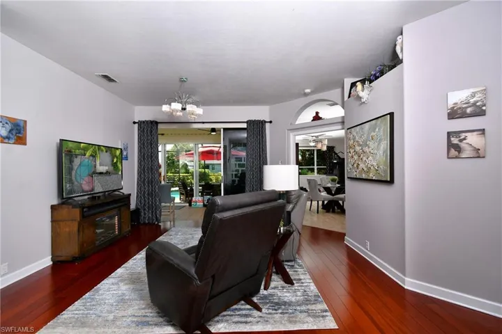 Living room with Engineered wood bamboo style floors and ceiling fan with notable chandelier