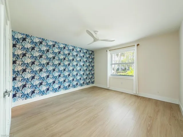 Unfurnished master bedroom suite featuring ceiling fan and light tile wood-style floors