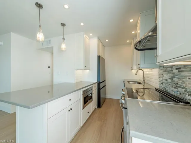 Fully modeled Kitchen with white cabinetry,    stainless steel appliances granite counters open to Living Area