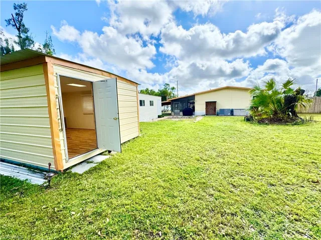 View of yard with a shed, an outbuilding, and fence