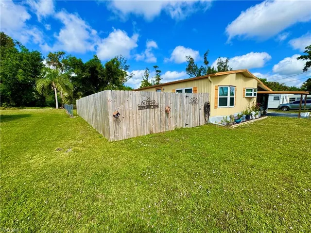 View of side of home featuring fence and a yard
