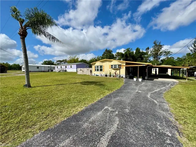View of front facade with a front lawn, an attached carport, and driveway