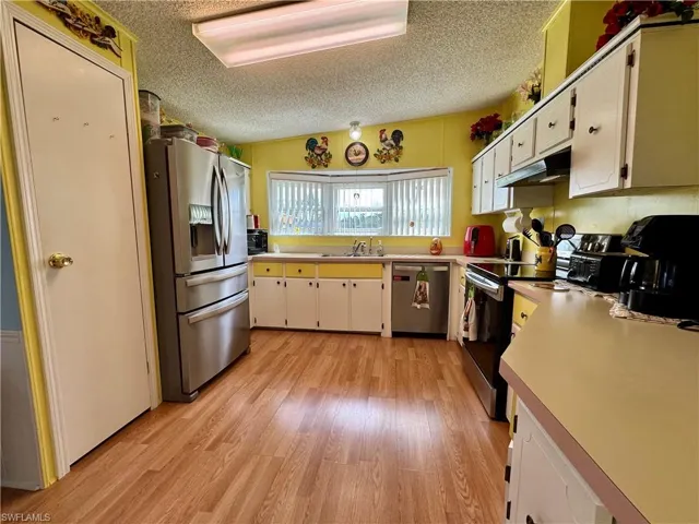 Kitchen featuring light countertops, light wood-style floors, appliances with stainless steel finishes, and a textured ceiling