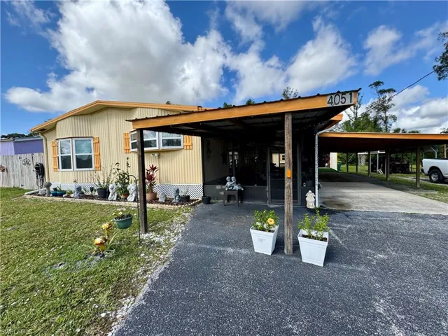 View of front of house featuring driveway, a carport, and a front yard