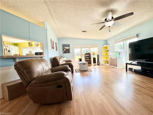 Living room featuring a textured ceiling, visible vents, wood finished floors, and a ceiling fan