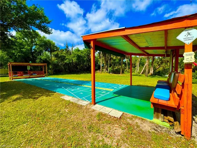 View of community featuring shuffleboard and a yard