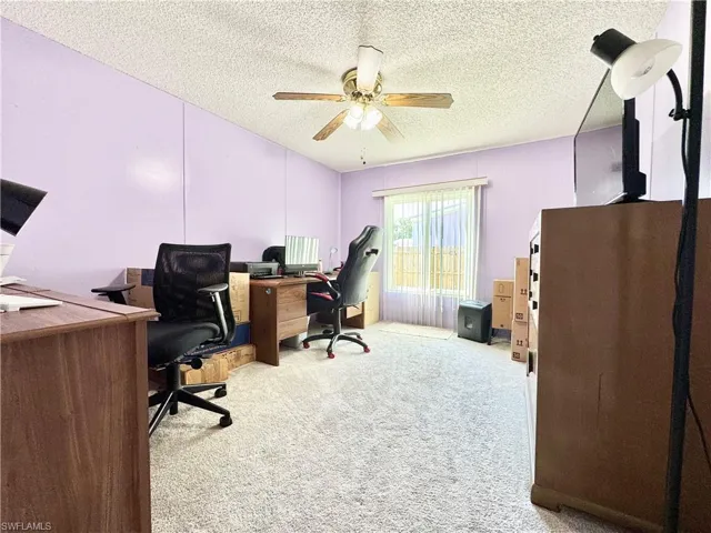 Home office with a textured ceiling, ceiling fan, and carpet