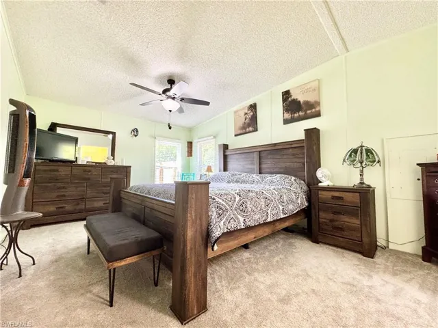 Bedroom with a textured ceiling, a ceiling fan, and carpet