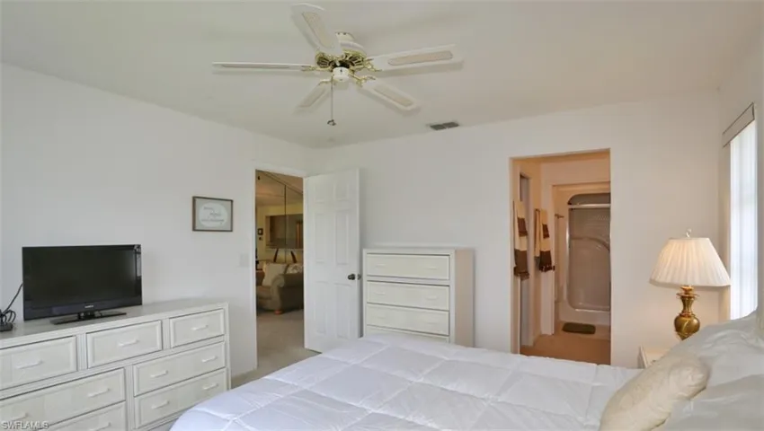 Carpeted bedroom with ceiling fan and connected bathroom