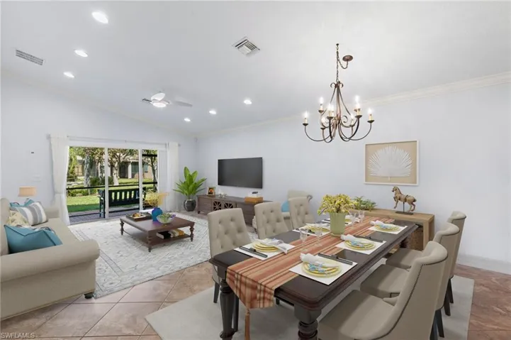 Living/Dining area with lake view, ornamental molding, vaulted ceiling, ceiling fan with notable chandelier, and light tile patterned floors