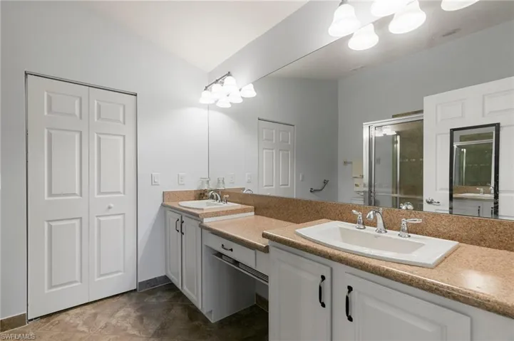 Master bathroom with vanity, lofted ceiling, and a shower with door