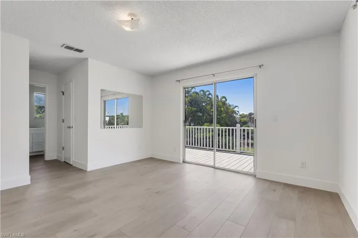 Spare room with light wood-type flooring and a textured ceiling