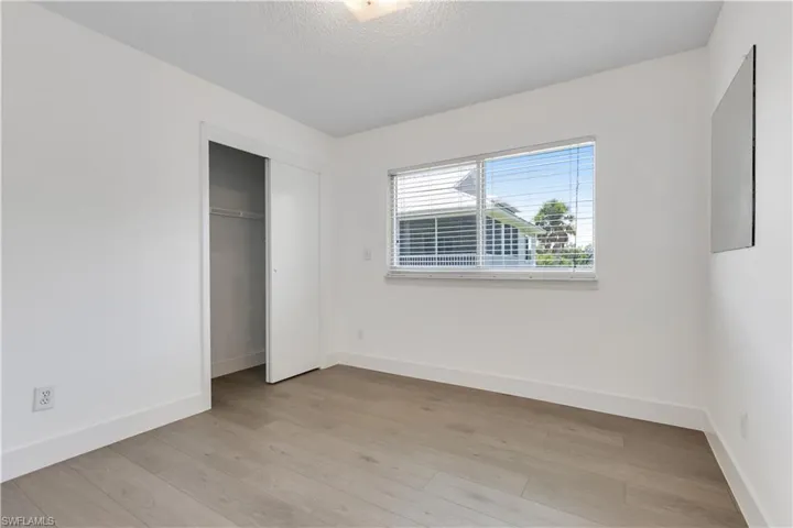 Unfurnished bedroom with light wood-type flooring, a closet, and a textured ceiling
