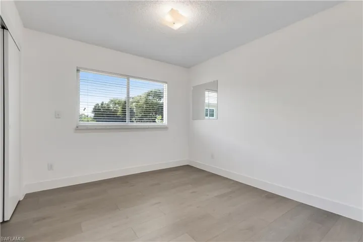 Empty room with a textured ceiling and light hardwood / wood-style flooring