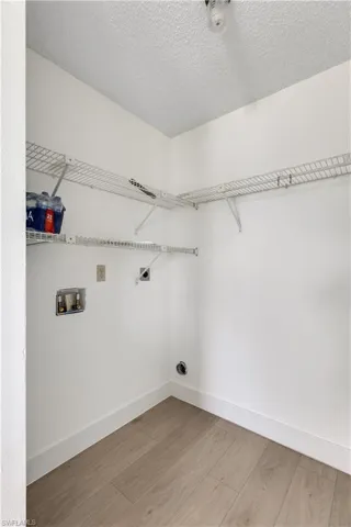 Laundry area featuring washer hookup, a textured ceiling, hardwood / wood-style floors, and hookup for an electric dryer