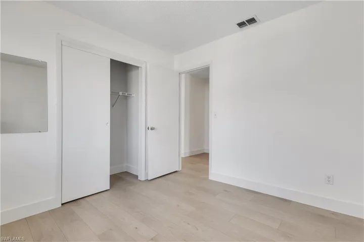 Unfurnished bedroom featuring a textured ceiling, light hardwood / wood-style flooring, and a closet