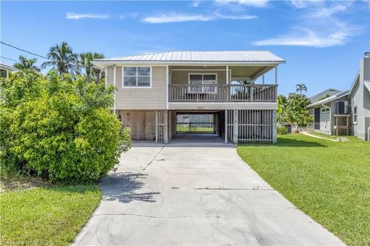 View of front of property featuring a porch, a carport, and a front lawn