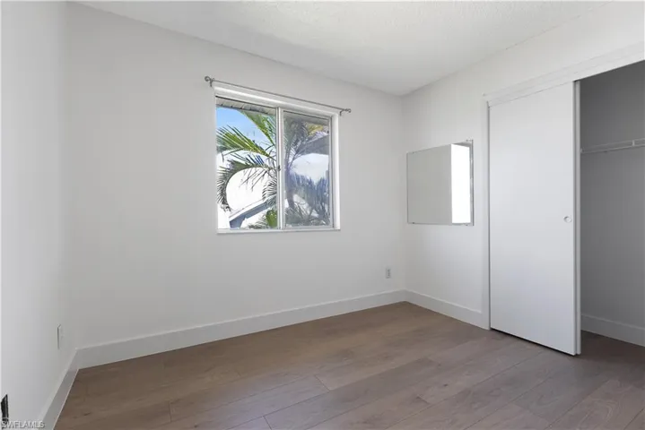 Unfurnished bedroom with a textured ceiling, a closet, and wood-type flooring