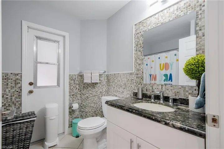 Bathroom featuring toilet, tasteful backsplash, vanity, and tile patterned floors