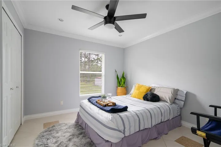 Tiled bedroom featuring a closet, ornamental molding, and ceiling fan